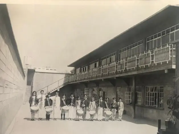 Niños de la Banda de Guerra escolar tocando tambores y trompetas, imagen en blanco y negro.