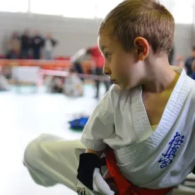 Niño con traje de karateca entrenando con un costal de Taekwondo.