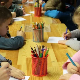 Niños haciendo tareas con lápices de colores y cuadernos en el Club de Tareas.