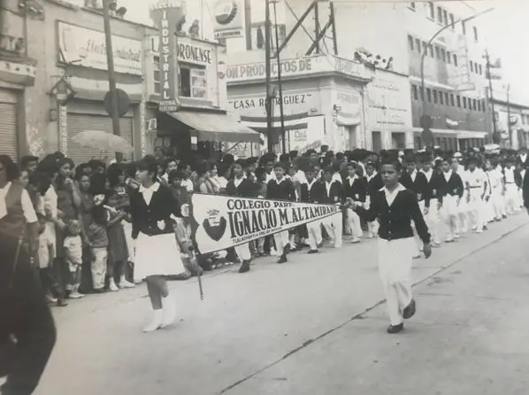 Dos niños del colegio sosteniendo el banderín en un desfile por las calles.